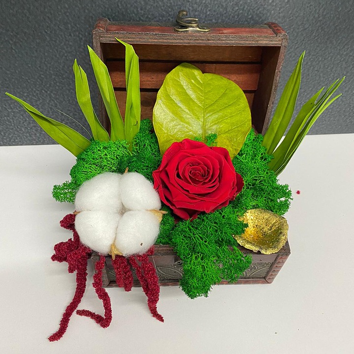 Aranjament floral cu trandafir criogenat rosu pe pat de licheni verzi in cutie tip cufar