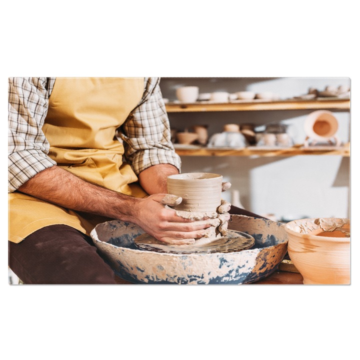 Tablou Canvas Maini masculine cu o oala ceramica pe roata O privire partiala la creatie, evidentiind frumusetea lucrului manual in ceramica. 40x25CM